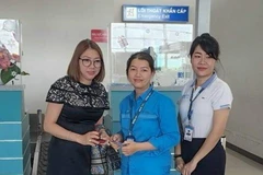 Chị Võ Thị Thùy Dung (giữa) bàn giao tài sản cho hành khách đánh rơi. (Ảnh: TTXVN phát)