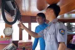 Kiểm ngư kiểm tra trang bị giám sát hành trình trên các tàu cá đang đánh bắt trên biển. (Ảnh: TTXVN phát)