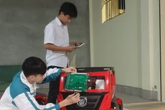 Em Phạm Đăng Minh (đứng) và Hoàng Văn Đồng nghiên cứu thực hiện đề tài. (Ảnh: Hải Yến/TTXVN)