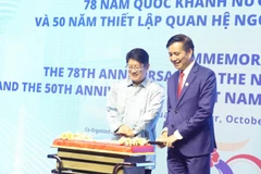 Đại sứ Đinh Ngọc Linh và Bộ trưởng Bộ Hợp tác và Phát triển Doanh nghiệp Malaysia Ewon Benedick tiến hành nghị thức cắt bánh chúc mừng. (Ảnh: An Nguyễn/TTXVN)