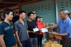 Chủ tịch Hội người Việt Nam tại tỉnh Attapeu Võ Văn Mừng trao tặng số tiền 1 triệu Kip cho 3 gia đình bị ảnh hưởng sau sự cố vỡ đập thủy điện. (Ảnh: Quang Thái/TTXVN)