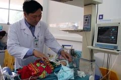 Bác sỹ Lò Văn Nhay kiểm tra sức khỏe của bệnh nhi Cà Văn Thắng tại phòng hồ sức sau mổ. (Ảnh: Diệp Anh/TTXVN)