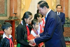 Chủ tịch nước Trần Đại Quang tặng quà cho các trẻ em có hoàn cảnh đặc biệt. (Ảnh: Nhan Sáng/TTXVN)