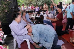 Các con đang thực hiện nghi lễ rửa chân tạ ơn đấng sinh thành tại Đại lễ Vu Lan báo hiếu. (Ảnh: Phạm Kiên/TTXVN)