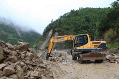 Máy móc san gạt bùn, đất đá bị sạt lở tại km75, Quốc lộ 4D từ Lai Châu đi Lào Cai. (Ảnh: Quý Trung/TTXVN)