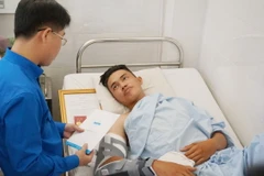 Đồng chí Phạm Hồng Sơn, Ủy viên Ban thường vụ Trung ương Đoàn, Bí thư Thành đoàn Thành phố Hồ Chí Minh trao huy hiệu “Tuổi trẻ dũng cảm” cho “hiệp sỹ” Đinh Phú Quý. (Ảnh: Đinh Hằng/TTXVN)