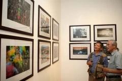 Nghệ sỹ nhiếp ảnh và khách tham quan triển lãm. (Ảnh: Thanh Tùng/TTXVN)