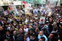 Người Palestine ở Nablus giơ cao những bức ảnh của người thân đang bị giam giữ trong các nhà tù của Israel trong một cuộc míttinh nhân Ngày Tù nhân Palestine. (Nguồn: Xinhua)