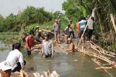 Gia cố lại bờ bao bị vỡ. (Ảnh: Hoàng Anh Tuấn/Vietnam+)