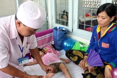 Bác sỹ chăm sóc 1 bệnh nhi mắc bệnh tay chân miệng. (Ảnh: Lê Huy Hải/TTXVN)