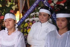 Bà Trần Thúy Liễu (giữa) và hai con trong đám tang nhà báo Hoàng Hùng. (Nguồn: Người Lao động)