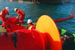 Các cơ quan chức năng dùng phao vây ngăn chặn sự cố tràn dầu ở cảng Dung Quất. (Nguồn: tinngan.vn)