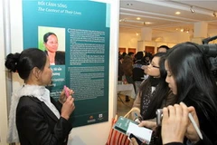 Bà mẹ đơn thân Trương Thị Minh đang kể về cuộc đời của mình qua từng bức ảnh. (Ảnh: Thái Bình/TTXVN)