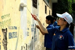 Các tình nguyện viên xóa bỏ quảng các rao vặt trái phép. (Ảnh: Đình Trân/TTXVN)