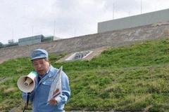 Một nhân viên của TEP đang diễn giải trước các ủy viên hội đồng địa phương về đoạn đê bao chắn sóng thần. (Nguồn: Kyodo)
