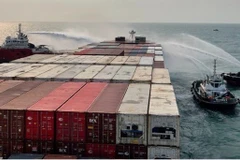 Lực lượng chữa cháy phun nước dập lửa trên tàu container APL CAIRO. (Ảnh: TTXVN)