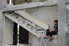 Em bé Palestine trở về căn nhà đã bị phá hủy trong các cuộc không kích của máy bay Israel xuống thị trấn Beit Lahia, Dải Gaza, khi lệnh ngừng bắn có hiệu lực, ngày 21/5/2021. (Ảnh: THX/TTXVN)
