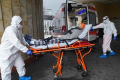 Nhân viên y tế chuyển bệnh nhân COVID-19 vào bệnh viện ở Vacsava (Ba Lan). (Ảnh: AFP/TTXVN)