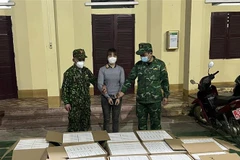 Dương Thị Nhân cùng số bộ xét nghiệm nhanh COVID-19 bị thu giữ. (Ảnh: TTXVN)