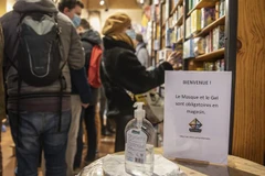 Bảng nhắc nhở người dân đeo khẩu trang và sát khuẩn tay để phòng dịch COVID-19 tại một cửa hàng ở Lille, miền Bắc nước Pháp, ngày 22/12/2021. (Ảnh: THX/TTXVN)