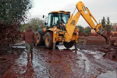 Người dân xúc bùn ra khỏi nhà. (Ảnh: AFP/TTXVN)