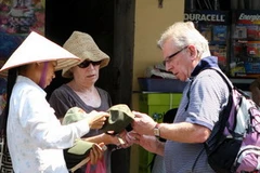 Du khách mua một món đồ lưu niệm tại phố cổ Hà Nội. (Ảnh: Trần Việt/TTXVN)