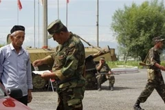 Lính Kyrgyzstan kiểm tra bằng lái xe của một người dân ở Osh. (Ảnh: AP)