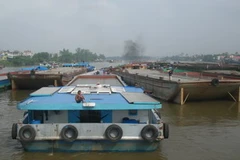 Hàng chục chiếc xà lan đang chờ triều cường xuống để qua cầu Bình Lợi. (Ảnh: Hoàng Tuấn/TTXVN)