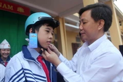 Hướng dẫn học sinh đội mũ bảo hiểm đúng cách. (Nguồn: TTXVN)