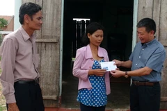 Đại diện Ban chỉ đạo Nhà nước về khắc phục hậu quả bom mìn sau chiến tranh trao tiền hỗ trợ cho gia đình nạn nhân. (Ảnh: Xuân Triệu/TTXVN)