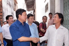 Bí thư Thành ủy Thành phố Hồ Chí Minh Đinh La Thăng thăm hỏi người dân nghèo sống trên và ven kênh Đôi (quận 8). (Ảnh: Thanh Vũ/TTXVN)