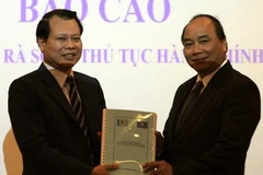 Bộ trưởng Bộ Tài chính Vũ Văn Ninh trao bộ thủ tục hành chính cho Bộ trưởng, Chủ nhiệm Văn phòng Chính phủ Nguyễn Xuân Phúc. (Ảnh: Phạm Hậu/TTXVN)