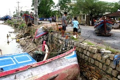 Tàu thuyền bị lũ, gió đánh bật lên trên đường. (Ảnh: Thế Lập/TTXVN)