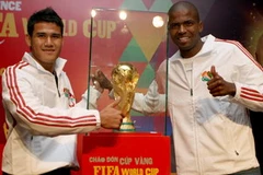 Cầu thủ Phan Thanh Bình và cầu thủ người Nam Phi Philani bên chiếc Cúp vàng tại buổi họp báo tối ngày 18/1. (Ảnh: Quang Nhật/TTXVN)