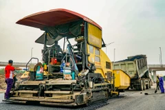 Nhà thầu thi công thảm nhựa nền đường một tuyến Quốc lộ. (Ảnh: Việt Hùng/Vietnam+)