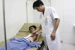 Bác sỹ thăm khám vết mổ cho bệnh nhân. (Ảnh: Thanh Thương/TTXVN)