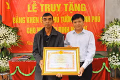 Phó Tổng Giám đốc Thông tấn xã Việt Nam Đinh Đăng Quang thừa ủy quyền của Thủ tướng Chính phủ trao Bằng khen của Thủ tướng Chính phủ cho gia đình cố Nhà báo Đinh Hữu Dư. (Ảnh: Minh Đức/TTXVN)