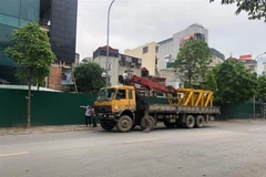 Phương tiện được tập kết tại chân tòa nhà 8B Lê Trực chuẩn bị cho việc tháo dỡ phần vi phạm giai đoạn 2 của tòa nhà. (Ảnh Mạnh Khánh/TTXVN)