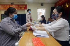 Người có công với cách mạng, hộ nghèo, hộ cận nghèo, đối tượng hưởng bảo trợ xã hội ở phường Mai Động, quận Hoàng Mai nhận tiền hỗ trợ từ gói hỗ trợ 62.000 tỷ đồng. (Ảnh: Trần Việt/TTXVN)