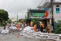 Đóng cát vào bao tải, đắp đê ngăn bùn và đất đá tràn. (Ảnh: Minh Quyết/TTXVN)