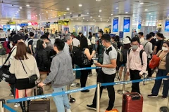 Hành khách xếp hàng dài chờ vào khu vực kiểm tra giấy tờ tùy thân và soi chiếu an ninh tại sân bay Nội Bài. (Ảnh: CTV/Vietnam+)