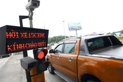Xe cá nhân đi qua một trạm thu phí không dừng. (Ảnh: Huy Hùng/TTXVN)