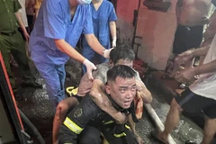 Lực lượng Cảnh sát Phòng cháy chữa cháy và cứu nạn cứu hộ đưa người bị nạn ra khỏi đám cháy. (Ảnh TTXVN phát)
