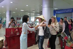 Các du khách Nga nhận món quà chiếc nón lá Việt Nam. (Ảnh: Tiên Minh/TTXVN)