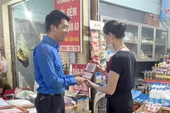 Đoàn viên, thanh niên là lực lượng nòng cốt trong tổ công nghệ số cộng đồng, hướng dẫn tiểu thương sử dụng mã QR code. (Ảnh: Đồng Thúy/TTXVN)