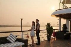 Du khách ngắm hoàng hôn sông Hồng trên tàu du lịch cao cấp. (Ảnh: TTXVN phát)