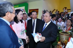 Thủ tướng Nguyễn Xuân Phúc thăm các gian hàng trưng bày sản phẩm tại hội nghị. (Ảnh: Thống Nhất/TTXVN)