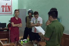 Cảnh sát điều tra đọc lệnh bắt các đối tượng. (Ảnh: Dư Toán/TTXVN)