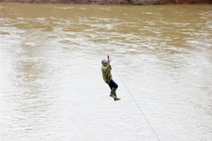 Người dân liều mình đu dây qua sông Pô Kô. (Ảnh: Khoa Chương/TTXVN)