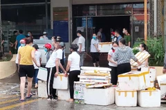 Nhân viên Siêu thị Ngọc Xuân dọn dẹp hàng hóa, đồ dùng sau vụ cháy. (Ảnh: Quốc Đạt/TTXVN)